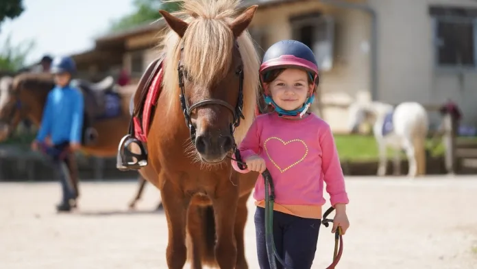 Fillette tenant un poney au poney-club